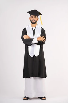 The concept of excellence, success and diligence, taking selfies in graduation gowns, celebrating the completion of university, portrait of a smiling young Arab Gulf Emirati graduate wearing a graduation cap and gown, standing with crossed hands looking at the camera with an expression of self-confidence, full body, white background
