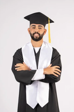 Taking selfies in graduation gowns, celebrating the completion of university, portrait of a smiling young Arab Gulf Emirati graduate wearing a graduation cap and gown, standing with crossed hands looking at the camera with an expression of self-confidence, the concept of excellence, success and diligence, white background