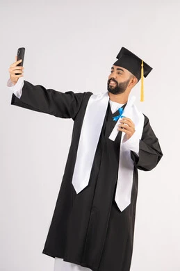 الاحتفاظ بالذكريات السعيدة، استخدام التقنية الحديثة، الاحتفال بإنهاء الدراسة الجامعية، بورتريه لشاب خريج عربي خليجي اماراتي يرتدي عباءه وقبعة التخرج  يقوم بالتقاط صورة سيلفي تذكارية عبر الهاتف المحمول، خلفية بيضاء
