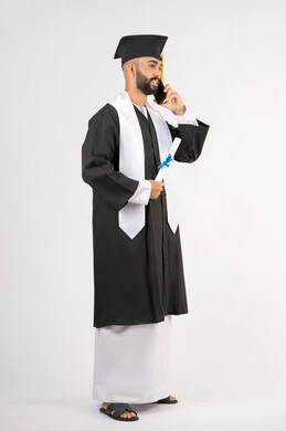 التواصل مع الأهل والأصدقاء، مفهوم الاجتهاد والتفوق، الاحتفال بإنهاء الدراسة الجامعية، استخدام التقنية الحديثة، بورتريه لشاب خريج عربي خليجي اماراتي يرتدي عباءه وقبعة التخرج يقوم بإجراء مكالمة عبر الهاتف المحمول، الجسم بالطول الكامل، خلفية بيضاء