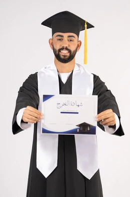 جودة التعليم في الامارات، الوصول لحلم النجاح، تعابير السعادة والسرور، مناسبة النجاح في الجامعة، الاحتفال بإنهاء الدراسة الجامعية، مفهوم الاجتهاد والتفوق، بورتريه لشاب خريج عربي خليجي اماراتي مبتسم يرتدي عباءة التخرج يمسك بيده الشهادة، خلفية بيضاء