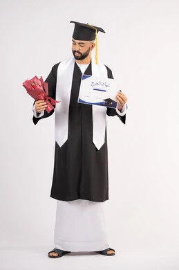 Expressions of happiness and joy at achieving the dream of success, a university occasion and celebration, celebrating the completion of university studies, the concept of diligence and excellence, a portrait of a smiling young Arab Gulf Emirati graduate wearing a graduation gown, holding a bouquet of flowers and a certificate, full body, white background