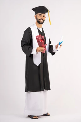 Expressions of happiness and joy at achieving the dream of success, a university occasion and celebration, celebrating the completion of university studies, the concept of diligence and excellence, a portrait of a smiling young Arab Gulf Emirati graduate wearing a graduation gown, holding a bouquet of flowers and a certificate, full body, white background