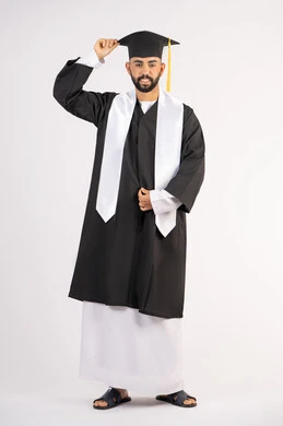 الاجتهاد والتفوق والنجاح، الاحتفال بإنهاء المرحلة الجامعية، تعابير السرور والسعادة، التقاط صور شخصية بثياب التخرج، بورتريه لشاب خريج عربي خليجي اماراتي مبتسم يرتدي عباءة التخرج يمسك بيده القبعة ينظر الى الكاميرا بإيماءات البهجة، الجسم بالطول الكامل، خلفية بيضاء