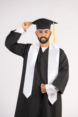 Hard work, excellence and success, celebrating the completion of university, expressions of joy and happiness, taking selfies in graduation gowns, portrait of a smiling young Arab Gulf Emirati graduate wearing a graduation gown, holding a hat in his hand, looking at the camera with joyful gestures, white background