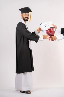 The concept of excellence and diligence, receiving the certificate with expressions of joy and happiness, side portrait of an Arab Gulf Emirati graduate wearing a graduation cap and gown taking a bouquet of flowers with gestures of happiness and joy, celebrating success and completing university studies, full body image, white background