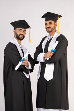 مناسبة واحتفال جامعي، الاحتفال بإنهاء المرحلة الجامعية، التقاط صور شخصية بثياب التخرج، بورتريه لشابين خريجين عربيين خليجيين اماراتيين مبتسمين يرتديان القبعة وعباءة التخرج ينظران الى الكاميرا بتعابير السرور، مفهوم التفوق والنجاح والاجتهاد، خلفية بيضاء