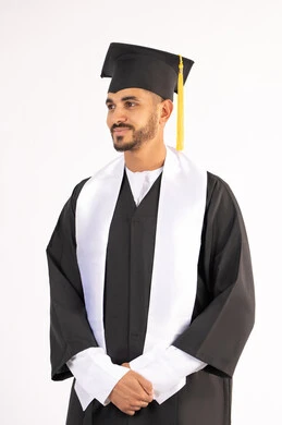 Excellence, success and diligence, celebrating the completion of university, standing up straight and taking selfies in graduation clothes, portrait of a smiling young Arab Gulf Emirati graduate wearing a graduation cap and gown looking at something with an expression of pleasure, white background