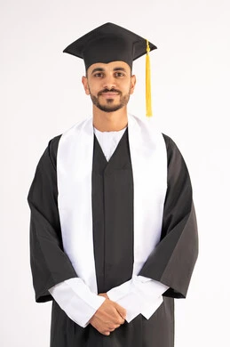 مفهوم التفوق والنجاح والاجتهاد، الاحتفال بإنهاء المرحلة الجامعية، الوقوف باستقامة والتقاط صور شخصية بثياب التخرج، بورتريه لشاب خريج عربي خليجي اماراتي مبتسم يرتدي القبعة وعباءة التخرج يتنظر الى الكاميرا بتعابير السرور، خلفية بيضاء