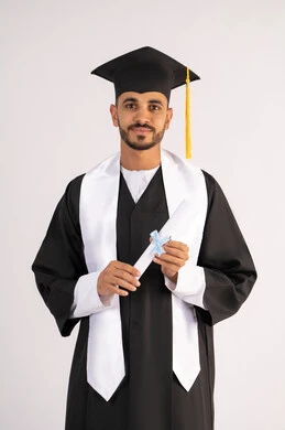 الاحتفال بإنهاء المرحلة الجامعية، تعابير السرور والسعادة بالنجاح، التقاط صور شخصية بثياب التخرج، بورتريه لشاب خريج عربي خليجي اماراتي مبتسم يرتدي القبعة وعباءة التخرج يحمل الشهادة ينظر الى الكاميرا بإيماءات البهجة، خلفية بيضاء