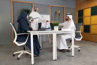 Collaboration and understanding among colleagues, developing strategic plans to achieve goals, using the whiteboard to ensure a clear and comprehensive understanding of the business, holding a meeting at the company's headquarters, a group of Arab Gulf Emirati employees learning work methods and professional development, team spirit and teamwork.
