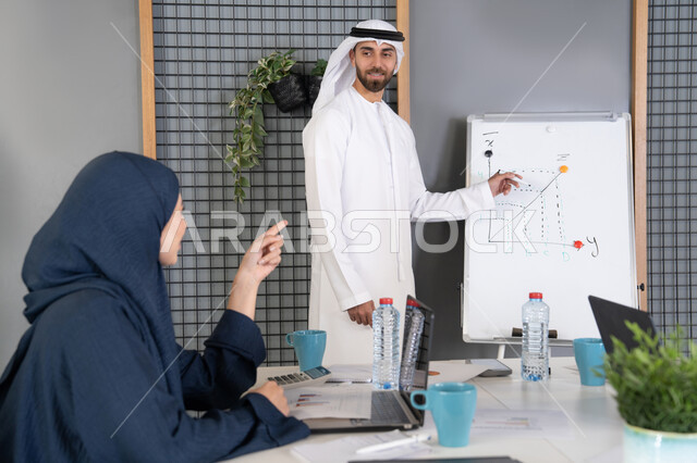 التنظيم والتخطيط الاستراتيجي لتحقيق الأهداف، استخدام السبورة لضمان فهم واضح وشامل للاعمال، عقد اجتماع داخل مقر الشركة، مجموعة من الموظفين العرب الخليجيين الاماراتيين يتعلمون اساليب العمل والتطوير المهني، روح الفريق الواحد والعمل الجماعي، التعاون والتفاهم بين الزملاء