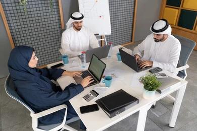 التركيز والعمل بدقة لتحقيق الاهداف، دمج العمل مع التقنية والتكنولوجيا، تطور الشركات الاماراتية، متابعة مشاريع الأعمال، مجموعة من الموظفين العرب الخلييجين الاماراتيين يقومون بإنجاز مهام العمل عبر جهاز الحاسوب داخل مقر الشركة