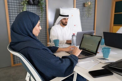 دمج العمل مع التقنية والتكنولوجيا، تطور الشركات الاماراتية، متابعة مشاريع الأعمال، مجموعة من الموظفين العرب الخلييجين الاماراتيين يقومون بإنجاز مهام العمل عبر جهاز الحاسوب داخل مقر الشركة، التركيز والعمل بدقة لتحقيق الاهداف