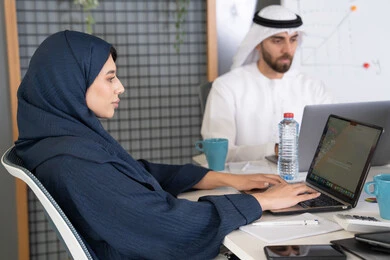 التركيز والعمل بدقة لتحقيق الاهداف، دمج العمل مع التقنية والتكنولوجيا، تطور الشركات الاماراتية، متابعة مشاريع الأعمال، مجموعة من الموظفين العرب الخلييجين الاماراتيين يقومون بإنجاز مهام العمل عبر جهاز الحاسوب داخل مقر الشركة