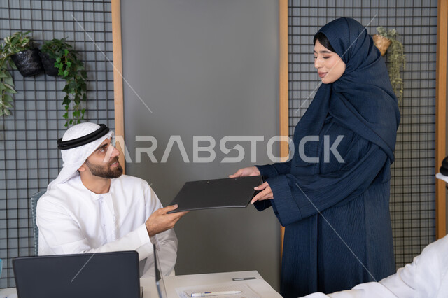 تقديم السيرة الذاتية لإجراء مقابلة توظيف، متابعة إنجازات الموظفين، الرغبة في تعلم اساليب العمل والتطوير المهني، زميلان عربيان خليجيان اماراتيان يقومان بإنجاز المهام عبر الحاسوب المحمول داخل المكتب، التعاون بين اعضاء الفريق