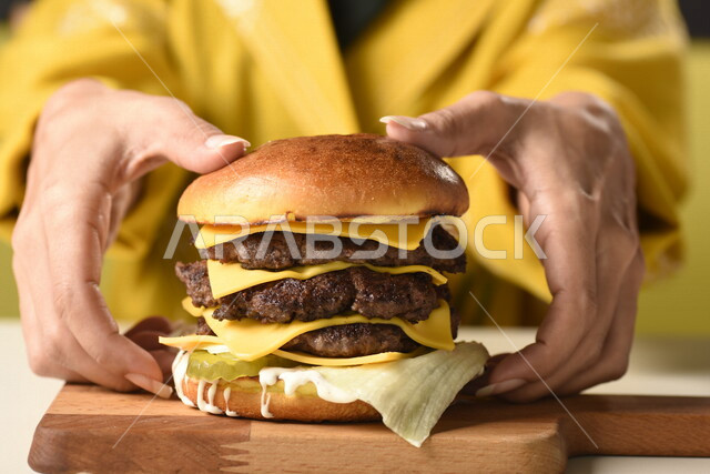 Burger sandwich with layers of meat and lettuce with melted cheese, enjoying eating burgers, fast food, harms from eating a lot of fast food