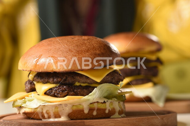 Burger sandwich with layers of meat and lettuce with melted cheese, enjoying eating burgers, fast food, harms from eating a lot of fast food