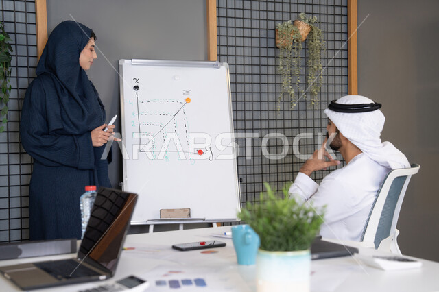 روح الفريق الواحد والعمل الجماعي، التفاهم والتعاون بين الزملاء ووضع الخطط الاستراتيجية لتحقيق الأهداف، استخدام السبورة لضمان فهم واضح وشامل للاعمال، عقد اجتماع داخل مقر الشركة، مجموعة من الموظفين العرب الخليجيين الاماراتيين يتعلمون اساليب العمل والتطوير المهني