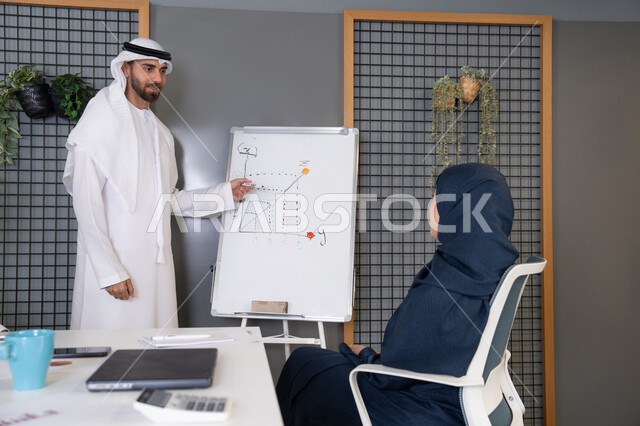 التنظيم والتخطيط الاستراتيجي لتحقيق الأهداف، استخدام السبورة لضمان فهم واضح وشامل للاعمال، عقد اجتماع داخل مقر الشركة، مجموعة من الموظفين العرب الخليجيين الاماراتيين يتعلمون اساليب العمل والتطوير المهني، روح الفريق الواحد والعمل الجماعي، التعاون والتفاهم بين الزملاء