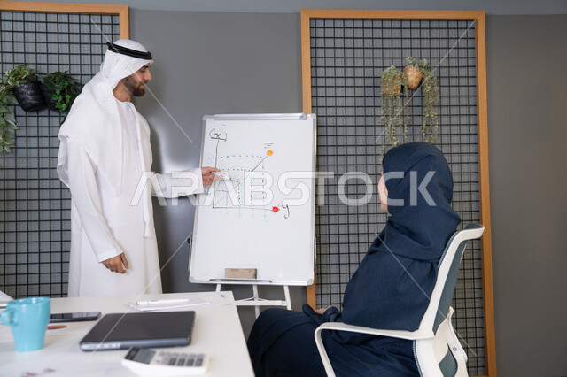 التنظيم والتخطيط الاستراتيجي لتحقيق الأهداف، استخدام السبورة لضمان فهم واضح وشامل للاعمال، عقد اجتماع داخل مقر الشركة، مجموعة من الموظفين العرب الخليجيين الاماراتيين يتعلمون اساليب العمل والتطوير المهني، روح الفريق الواحد والعمل الجماعي، التعاون والتفاهم بين الزملاء