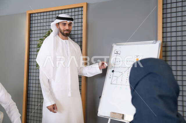 استخدام السبورة لضمان فهم واضح وشامل للاعمال، مجموعة من الموظفين العرب الخليجيين الاماراتيين يعقدون اجتماع داخل مقر الشركة، تعلم اساليب العمل والتطوير المهني، العمل الجماعي وروح الفريق، التفاهم والتعاون بين الزملاء ووضع الخطط الاستراتيجية لتحقيق الأهداف