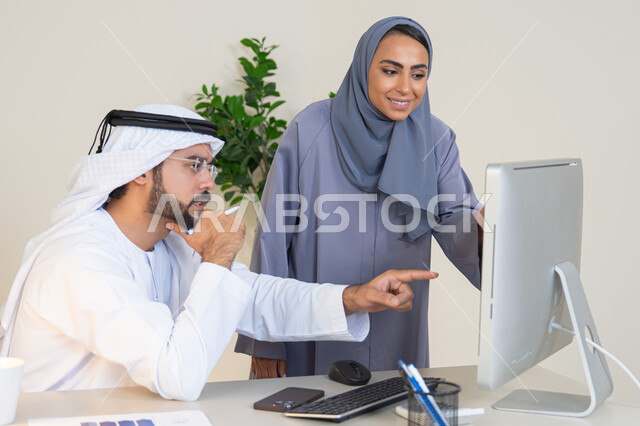 التفاهم والتعاون بين الزملاء ووضع الخطط الاستراتيجية، عقد اجتماع داخل مقر الشركة، موظفان عربيان خليجيان اماراتيان يتعلمان اساليب العمل والتطوير المهني، الاشارة باصبع السبابة الى شاشة الحاسوب، تبادل الخبرات والمعلومات لتحقيق الاهداف، روح الفريق الواحد والعمل الجماعي