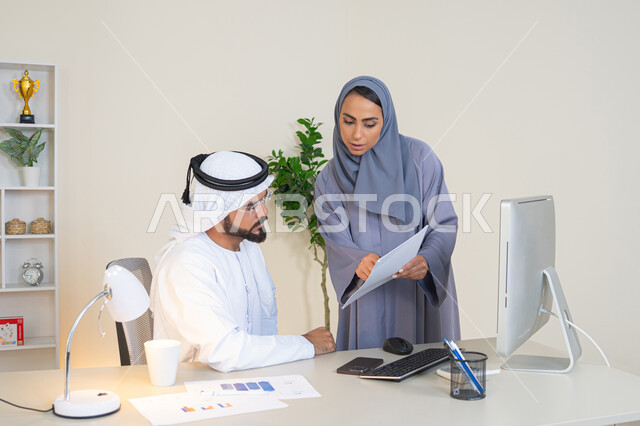 Discussion and understanding between employees, exchange of experiences and information to achieve goals, team spirit and teamwork, understanding and cooperation between colleagues and development of strategic plans, holding a meeting at the company headquarters, two Arab Gulf Emirati employees learning work methods and professional development