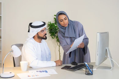 تبادل الخبرات والمعلومات لتحقيق الاهداف، روح الفريق الواحد والعمل الجماعي، التفاهم والتعاون بين الزملاء ووضع الخطط الاستراتيجية، عقد اجتماع داخل مقر الشركة، موظفان عربيان خليجيان اماراتيان يتعلمان اساليب العمل والتطوير المهني، النقاش والتفاهم بين الموظفين
