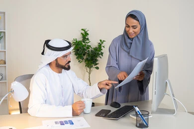 Cooperation and understanding between colleagues and the development of strategic plans, holding a meeting at the company's headquarters, two Arab Gulf Emirati employees learning work methods and professional development, discussion and understanding between employees, exchanging experiences and information to achieve goals, team spirit and teamwork.