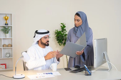 تبادل الخبرات والمعلومات لتحقيق الاهداف، روح الفريق الواحد والعمل الجماعي، التفاهم والتعاون بين الزملاء ووضع الخطط الاستراتيجية، عقد اجتماع داخل مقر الشركة، موظفان عربيان خليجيان اماراتيان يتعلمان اساليب العمل والتطوير المهني، النقاش والتفاهم بين الموظفين