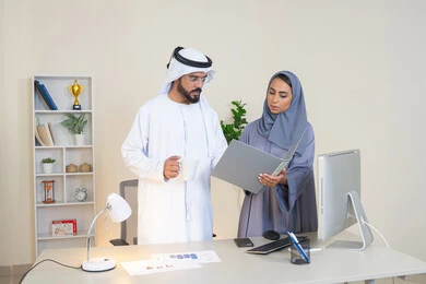 النقاش والتفاهم بين الموظفين، تبادل الخبرات والمعلومات لتحقيق الاهداف، روح الفريق الواحد والعمل الجماعي، التفاهم والتعاون بين الزملاء ووضع الخطط الاستراتيجية، عقد اجتماع داخل مقر الشركة، موظفان عربيان خليجيان اماراتيان يتعلمان اساليب العمل والتطوير المهني