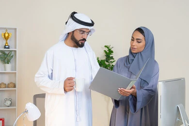 تبادل الخبرات والمعلومات لتحقيق الاهداف، روح الفريق الواحد والعمل الجماعي، التفاهم والتعاون بين الزملاء ووضع الخطط الاستراتيجية، عقد اجتماع داخل مقر الشركة، موظفان عربيان خليجيان اماراتيان يتعلمان اساليب العمل والتطوير المهني، النقاش والتفاهم بين الموظفين