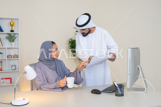 Discussion and understanding between employees, exchange of experiences and information to achieve goals, team spirit and teamwork, cooperation between colleagues and development of strategic plans, holding a meeting at the company headquarters, two Arab Gulf Emirati employees learning work methods and professional development.