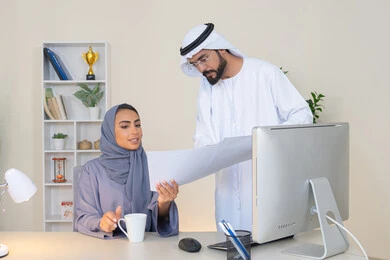 Exchange of experiences and information to achieve goals, team spirit and teamwork, cooperation between colleagues and development of strategic plans, holding a meeting at the company headquarters, two Arab Gulf Emirati employees learning work methods and professional development, discussion and understanding between employees