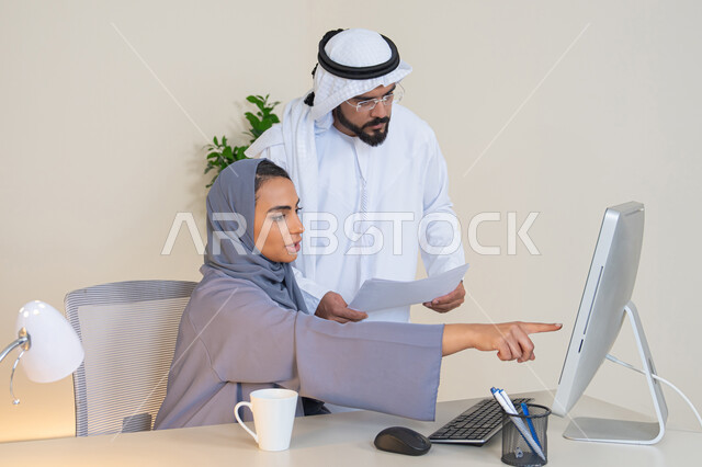 التفاهم والتعاون بين الزملاء ووضع الخطط الاستراتيجية، عقد اجتماع داخل مقر الشركة، موظفان عربيان خليجيان اماراتيان يتعلمان اساليب العمل والتطوير المهني، الاشارة باصبع السبابة الى شاشة الحاسوب، تبادل الخبرات والمعلومات لتحقيق الاهداف، روح الفريق الواحد والعمل الجماعي