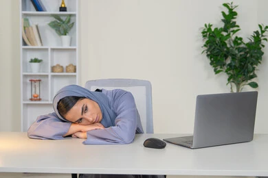 سيدة اماراتية تستخدم التقنية الحديثة المتطورة في المكتب، امراة عربية خليجية سعودية محجبة ترتدي العباءة تجلس خلف الطاولة بإيماءات الملل, محاولة ايجاد حل لمشكلة ما, شرود الذهن والتفكير، مهنة ووظيفة مكتبية، العمل في شركات الخليج العربي، الشعور بالضجر والملل