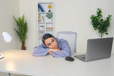 امراة عربية خليجية سعودية محجبة ترتدي العباءة تجلس خلف الطاولة بإيماءات الملل, محاولة ايجاد حل لمشكلة ما, شرود الذهن والتفكير، مهنة ووظيفة مكتبية، العمل في شركات الخليج العربي، الشعور بالضجر والملل، سيدة اماراتية تستخدم التقنية الحديثة المتطورة في المكتب