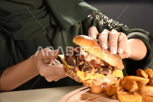  ساندويش البرجر بطبقات اللحم والخس مع الجبنه الذائبه,  إمرأه عربيه سعوديه خليجيه تتناول البرجر, الاستمتاع باكل البرجر, مأكولات سريعه, اضرار الاكثار من  تناول الوجبات السريعه