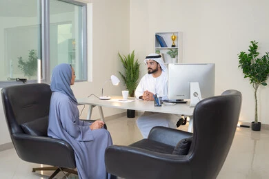 Understanding and cooperation between colleagues and developing strategic plans, holding a meeting at the company headquarters, two Arab Gulf Emirati employees learning work methods and professional development, exchanging experiences and information to achieve goals, team spirit and teamwork, using the computer
