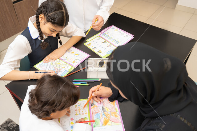 تنمية قدرات الطفل، صورة مقربة لام عربية خليجية اماراتية ترتدي العباءه السوداء تجلس على الطاولة تقوم بتعليم ابنائها، الانشطة التعليمية، تعليم وتطوير والاهتمام بالابناء، استغلال أوقات الفراغ بالأنشطة الترفيهية الممتعة