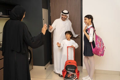 أجواء صباحية عائلية داخل المنزل، بداية يوم دراسي جديد، رجل عربي خليجي إماراتي يرتدي الكندورة والغترة يستعد للنزول مع اولادة، ام عربيه خليجيه اماراتية ترتدي العباءه تقوم بتوديع ابنائها عند الذهاب إلى المدرسة