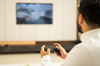 دمج المتعة والتسلية مع العالم الالكتروني, صورة مقربة ليدين رجل عربي خليجي سعودي يرتدي الثوب الأبيض يمسك بيده عصا التحكم, العالم الرقمي الترفيهي, قضاء أوقات مسلية بألعاب الفيديو, استخدام الأجهزة والتقنيات الحديثة والمتطورة