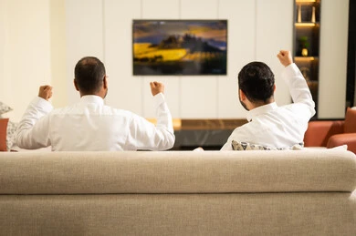 تعبيرات يد دليل الحماس والتفاعل مع المنتخب، الشغف بمتابعة المباريات، ايماءات الحماس بالفوز وتسجيل الأهداف، قضاء وقت ممتع مع الأصدقاء في المنزل، صديقان عربيان خليجيان سعوديان يشاهدان مباراة كرة القدم في غرفة المعيشة، الجلوس في غرفة المعيشة على آريكة مريحة