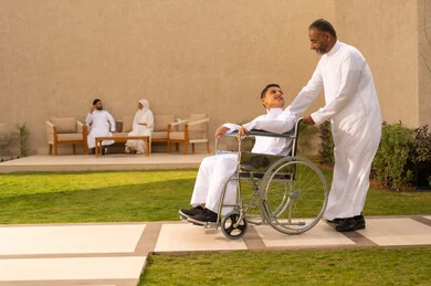 ولد سعودي مقعد يجلس على كرسي متحرك، تحسين حياة أصحاب الهمم وتأمين احتياجاتهم الخاصة, أدوات تساعد مرضى ذوي الإعاقة الحركية على التنقل بسهولة, رجل مسن عربي خليجي سعودي يرتدي الزي التقليدي برفقة ابنه في إحدى الشاليهات للاستمتاع بالهواء الطلق،  خلفية رجل وإمراة