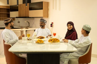 Family visits and gatherings during Islamic holidays and occasions, an Arab Gulf Omani family gathers around the iftar table in the month of Ramadan, celebrating the arrival of the blessed month of Ramadan, Ramadan decorations and ornaments, a month of goodness and blessings, Islamic religious occasions.