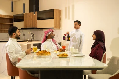 المأكولات والمقبلات الرمضانيه المتنوعه والشهية، عائلة عربية خليجية سعودية على مائدة الافطار فى شهر رمضان الكريم في المنزل، ابن يرتدي الثوب السعودي التقليدي يحمل فانوس رمضان، اجواء وزينة واكسسوارات رمضانية، شهر الخير والبركة، قضاء وقت ممتع مع الأسرة