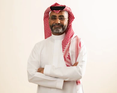 الاهتمام بالمظهر الخارجي ، صورة شخصية للوثائق الرسمية، مفهوم الوسامة والاناقة، بورتريه لرجل كبير بالسن عربي خليجي سعودي يرتدي الثوب والشماغ التقليدي والنظارة الطبية  يقف بأيدي متقاطعة وينظر إلى الكاميرا بإيماءات السعادة والسرور، خلفية بيضاء