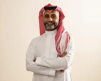 Attention to appearance, a portrait for official documents, the concept of handsome and elegance, a portrait of an elderly Arab Gulf Saudi man wearing the traditional thobe and ghutrah and medical glasses, standing with crossed arms and looking at the camera with gestures of happiness and joy, white background.