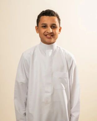 Attention to appearance, the concept of handsome and elegance, looking at the camera with gestures of happiness and joy, a personal photo for official documents, a portrait of a smiling Arab Gulf Saudi boy wearing traditional attire, white background.